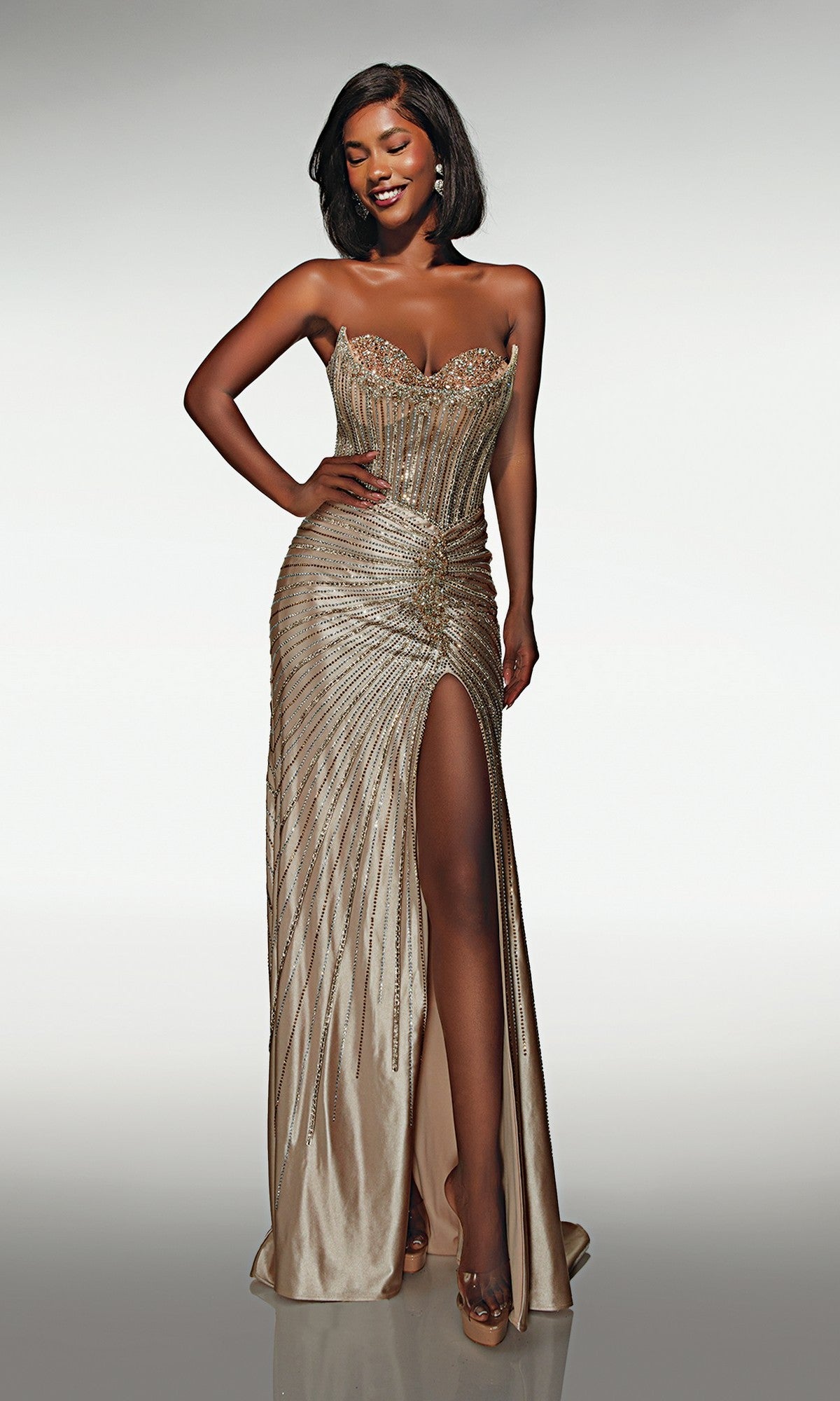 A woman poses against a plain background wearing the Alyce 62142 long prom dress, featuring a strapless satin design with a sweetheart neckline, beaded details, and a high slit.